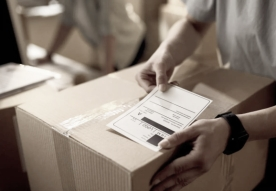 A person attaching a label to a cardboard box.