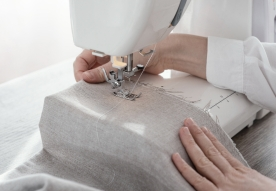 A person using a sewing machine on fabric.