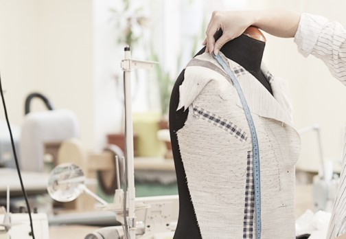 Person tailoring on a dress form