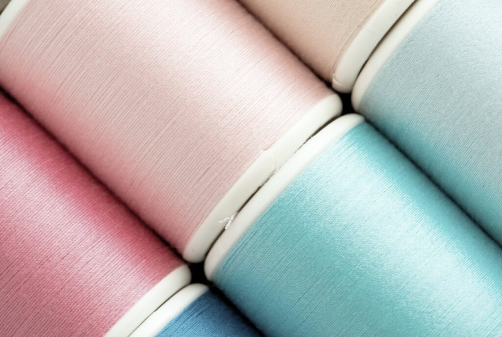 Close-up of colorful thread spools in pink, blue, and beige.