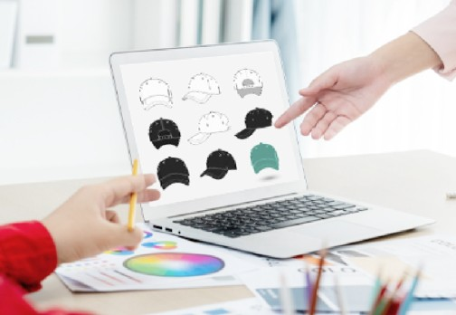 Team discussing custom cap designs on laptop in office