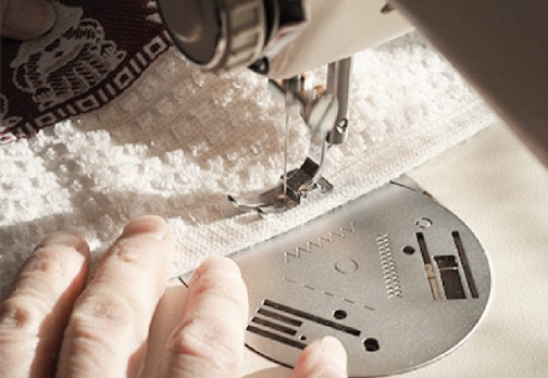 Close-up of sewing machine stitching white fabric