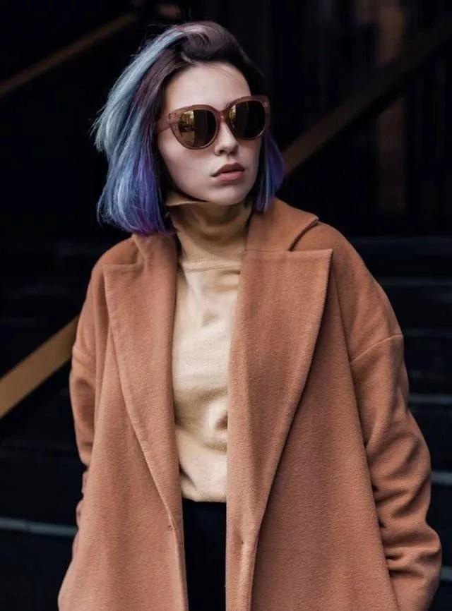A woman wearing stylish clothes including a brown coat and beige turtleneck