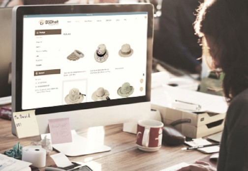 Woman browsing straw hats on an ecommerce website at office desk