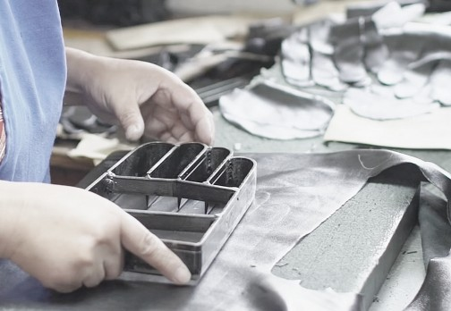 Hands using a cutter on leather material