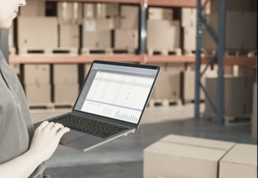 Person using laptop for inventory in warehouse