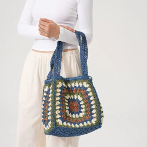 Model carrying blue crochet straw tote bag, scale on shoulder
