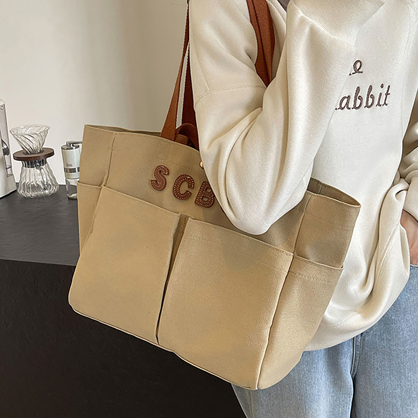 Canvas tote handbag carried on shoulder, beige color, everyday work and commuting.