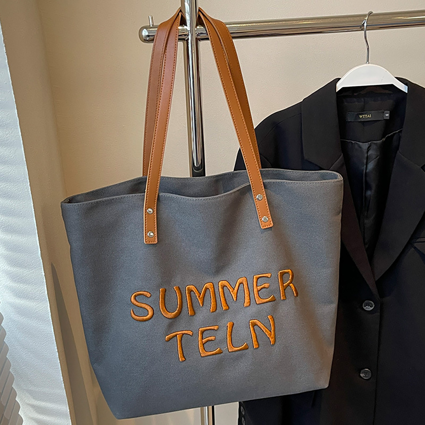 Grey canvas tote bag with orange embroidery and long straps for bulk customization.