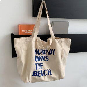 Canvas tote with bold front print hanging on wall hook, large capacity shopper bag.