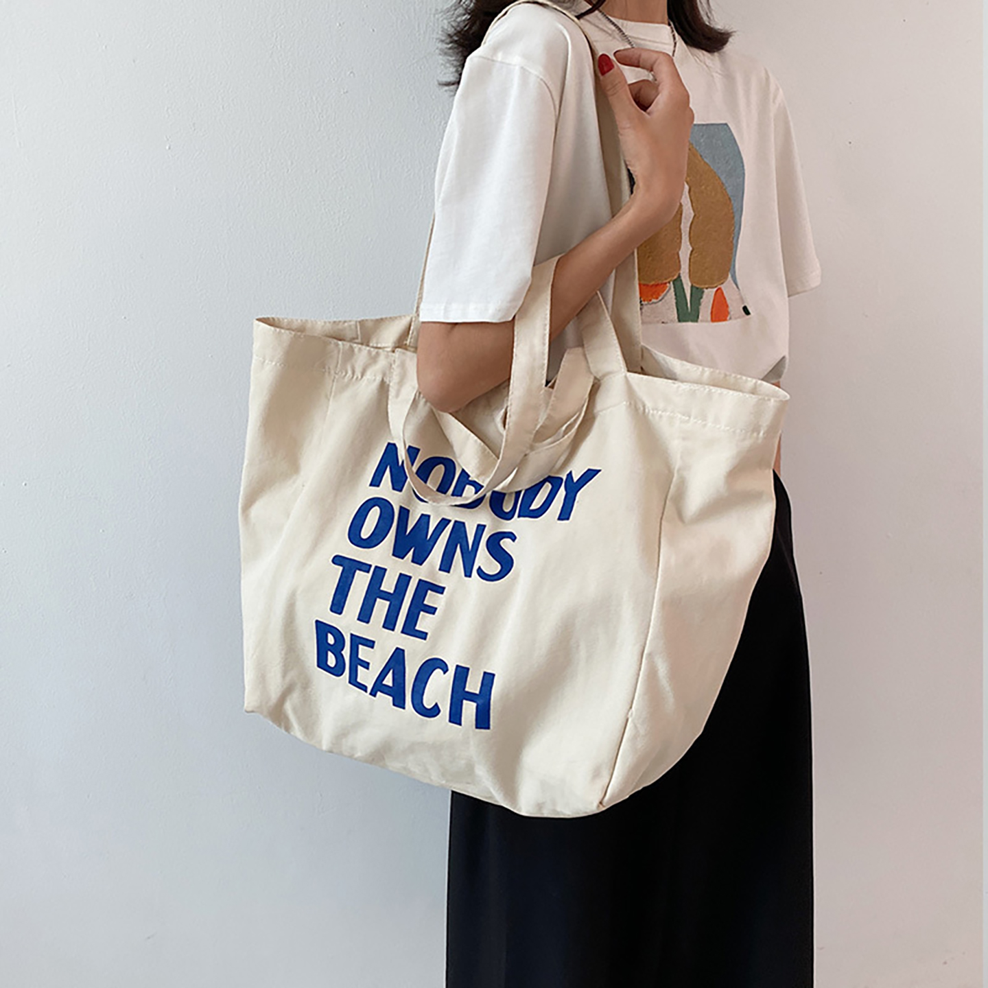 Model carrying oversized canvas tote bag on shoulder, everyday beach and weekender tote.