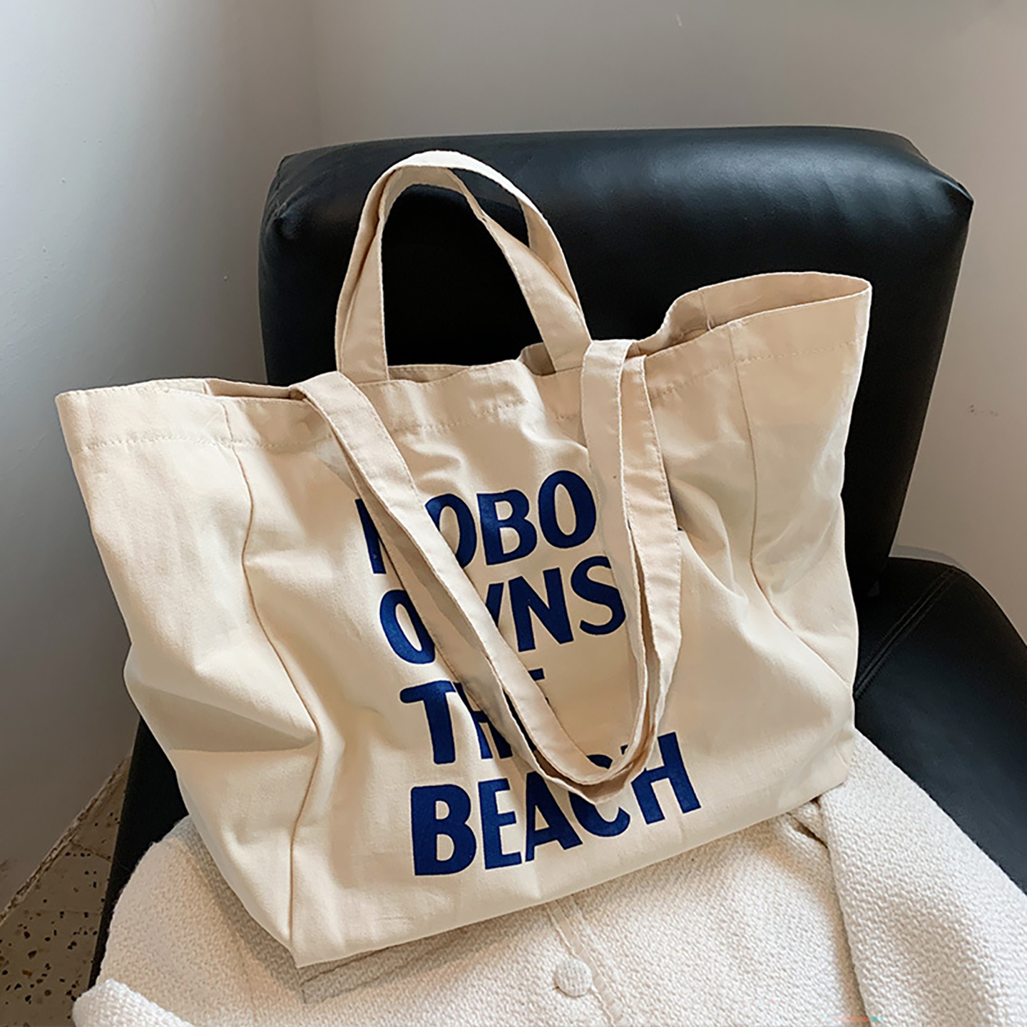Canvas tote resting on chair showing large front print and soft rectangular shape.