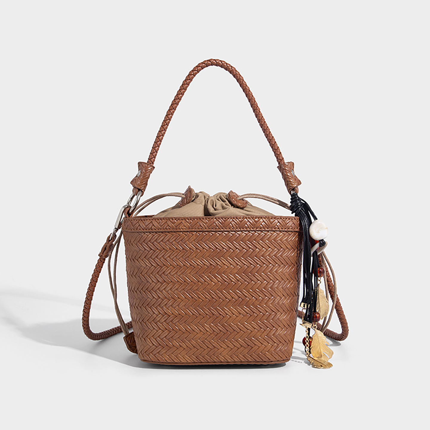 Brown woven bucket handbag showing braided top handle and detachable strap.