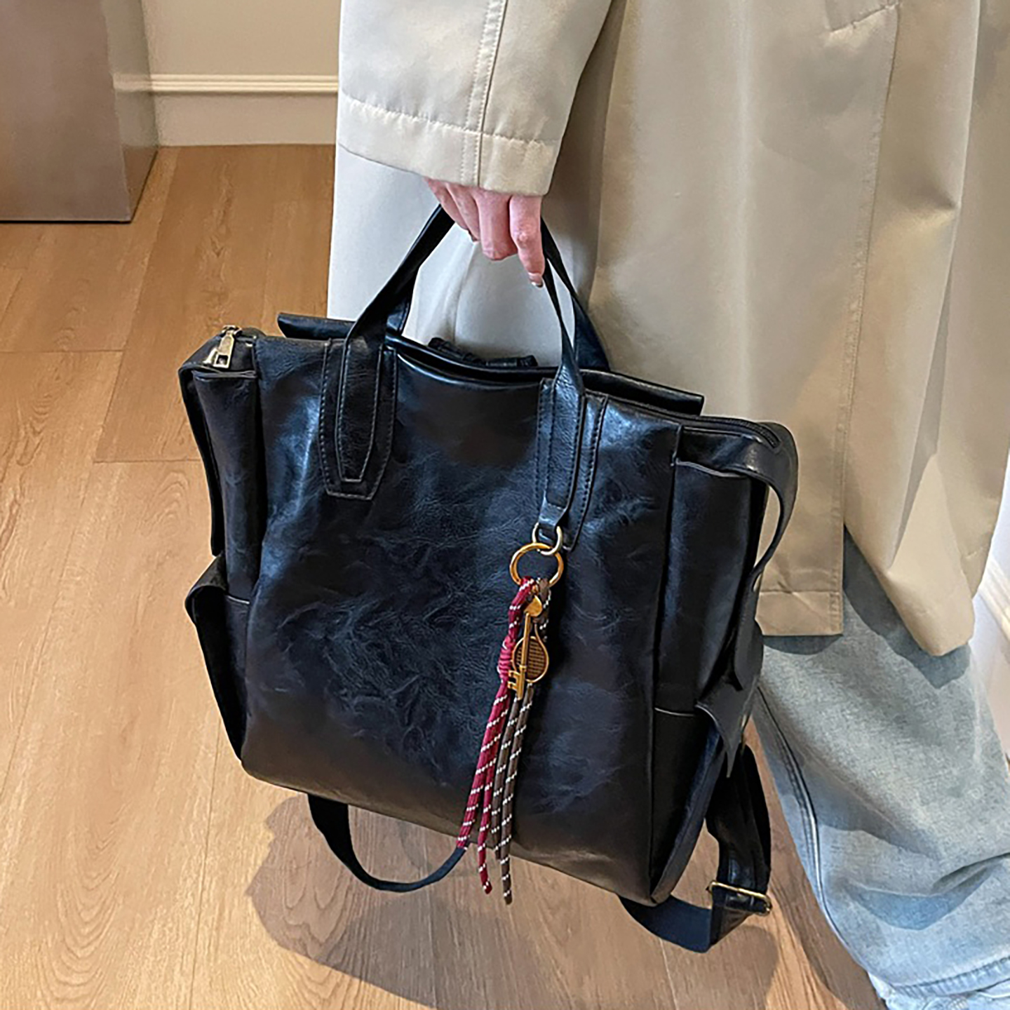 Woman carrying black convertible tote bag by hand as shoulder bag