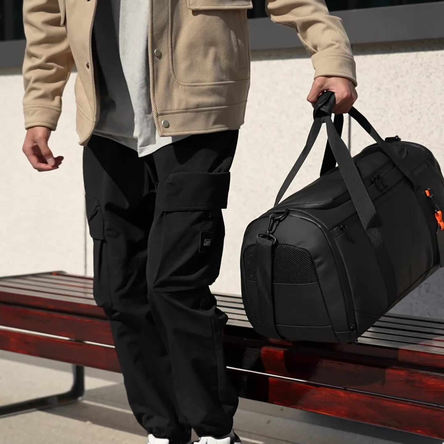Model carrying black duffel bag in streetwear outfit, highlighting versatile gym-to-travel functionality and modern aesthetic.