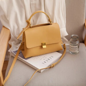 Mustard yellow small square crossbody bag with top handle and gold-tone clasp.