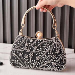 Top-handle black beaded clutch bag with pearl clasp held in hand.
