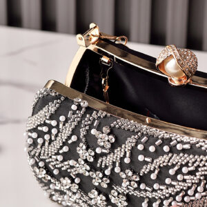 Close-up of pearl kiss-lock and metal frame on black beaded clutch.