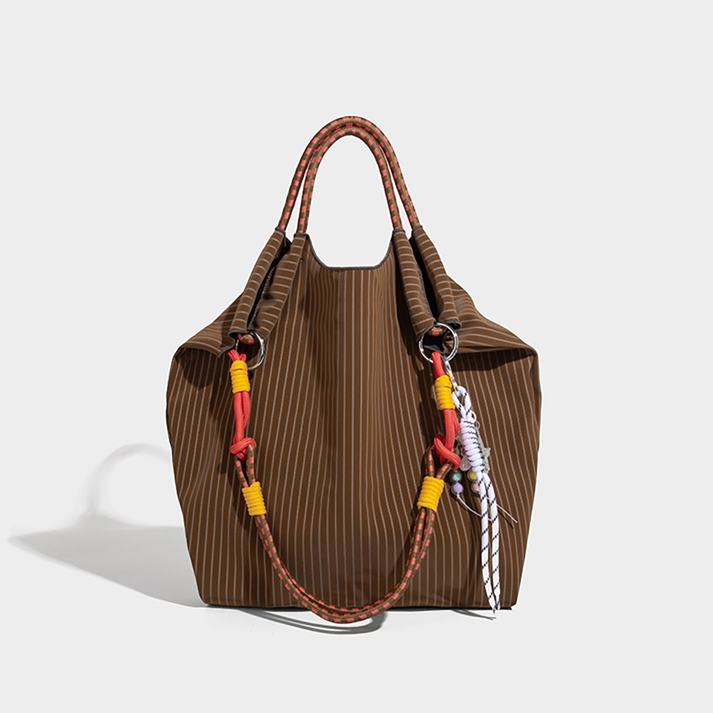 Front view of coffee brown women's shoulder bag with striped fabric and fun accents