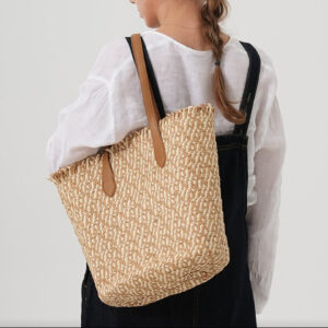 Model wearing beige large beach bag over shoulder casually