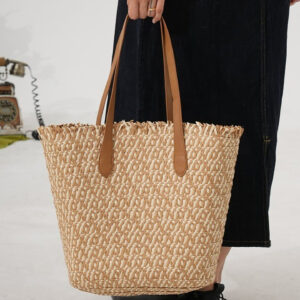 Model holding color-block bucket straw bag in studio setting