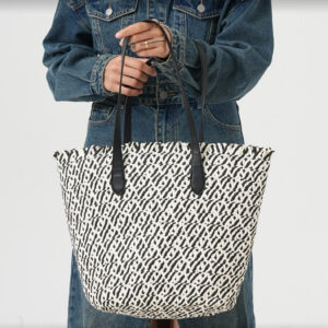 Model holding black-white bucket straw bag in studio setting