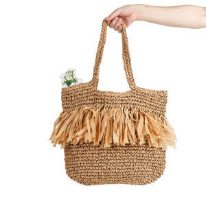 Model carrying the large woven straw tote on the shoulder, demonstrating size and fit.
